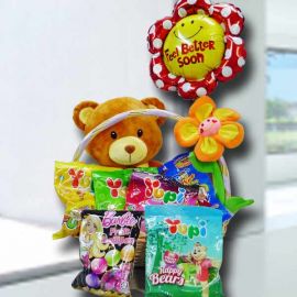 12 inch bear sits in a basket, surrounded with sweets and a balloon
